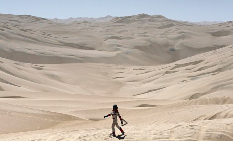 Erik Wevers, Dutch co-driver of the Mitsubishi driven by Fabian Lurquin, from Belgium, walks along the desert after their car got stuck in the sand during the 12th stage of the 2012 Argentina-Chile-Peru Dakar Rally between Arequipa and Nazca in Peru, Jan. 13, 2012. (AP Photo/Martin Mejia)